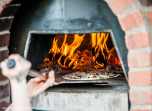 Wood fired pizza going into oven